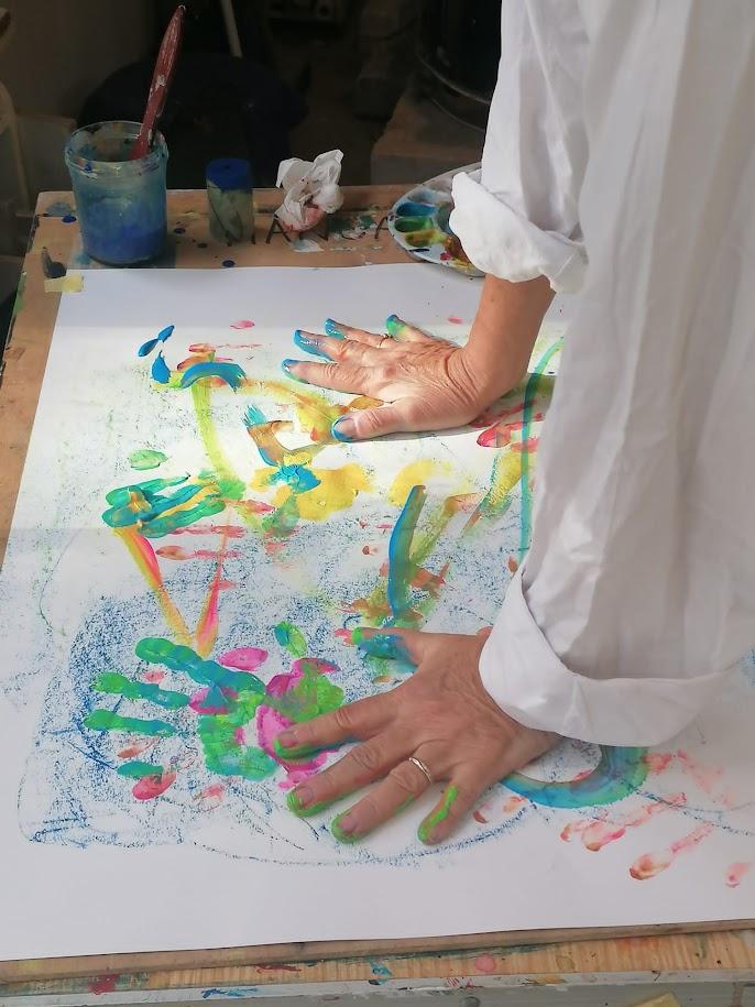 Main couverte de peinture posée sur une grande feuille pendant une séance d'art-thérapie